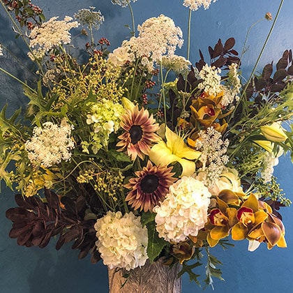 This tall flower arrangement of Queen Anne’s lace, privet berries, sunflowers, cymbidium orchids, hydrangeas, yellow lilies and brown cotinus foliage made quit a splash with our customer. 