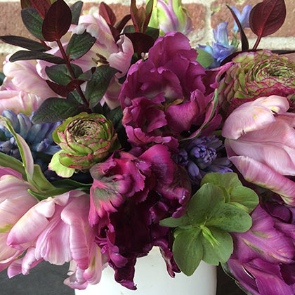 This deep and moody flower arrangement combines lavender and purple parrot tulips with green hellebore, blue hyacinth and Ranunculus in purple and green.