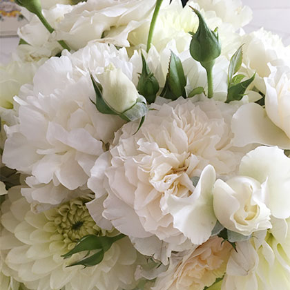 A beautiful centerpiece with Iceberg roses mixed with white peonies and pastel dahlias.