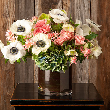 White anemones combined with coral pink roses and small hydrangea complete this Winter flower arrangement.