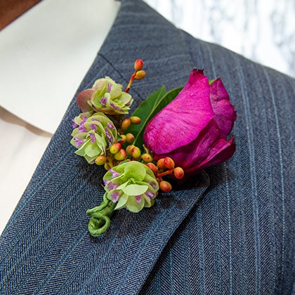 A garden rose is hand tied with flowering oregano and bright summer berries to create this beautiful boutonniere.