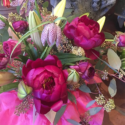 Crimson peonies are simply arranged with eucalyptus and a few lilies in this festive flower arrangement for delivery.