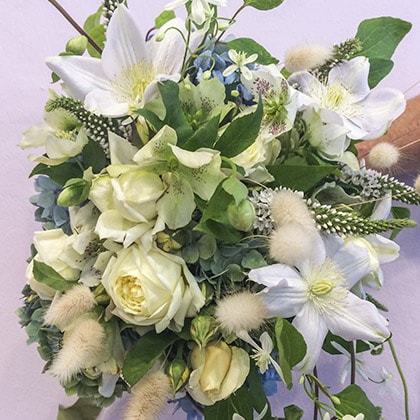 Hand tied bridal bouquet of clematis, hellebore, garden roses, Lysimachia with pale blue Tweedia tucked in around the edges.