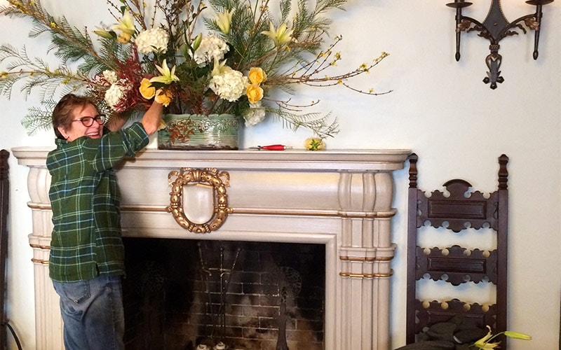 Large floral installation being installed on the fireplace mantle at The International House in Berkeley, California.